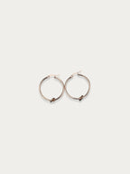 Front view of oversized rose gold knot hoop earrings on a neutral background.