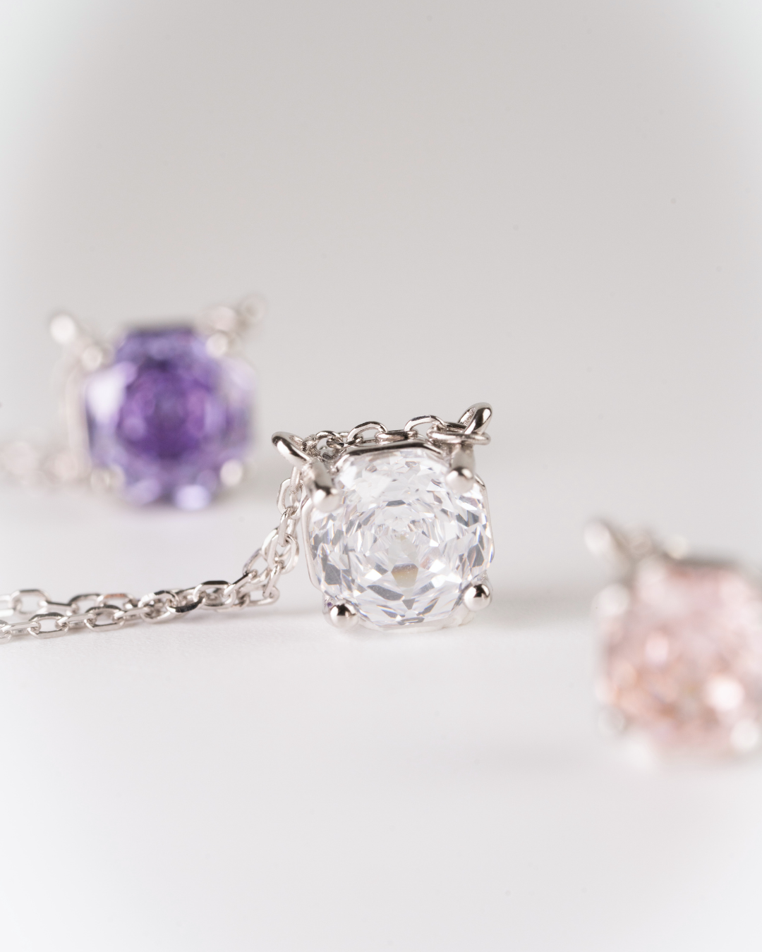 Close-up of a rose cut stone in silver necklace with a large diamond pendant on a light background