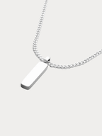 Macro detail of Axis cuboid bar pendant in silver titanium on curb chain