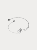 A delicate silver chain bracelet featuring a central double-ring design and a small circular charm, displayed on a light gray background.