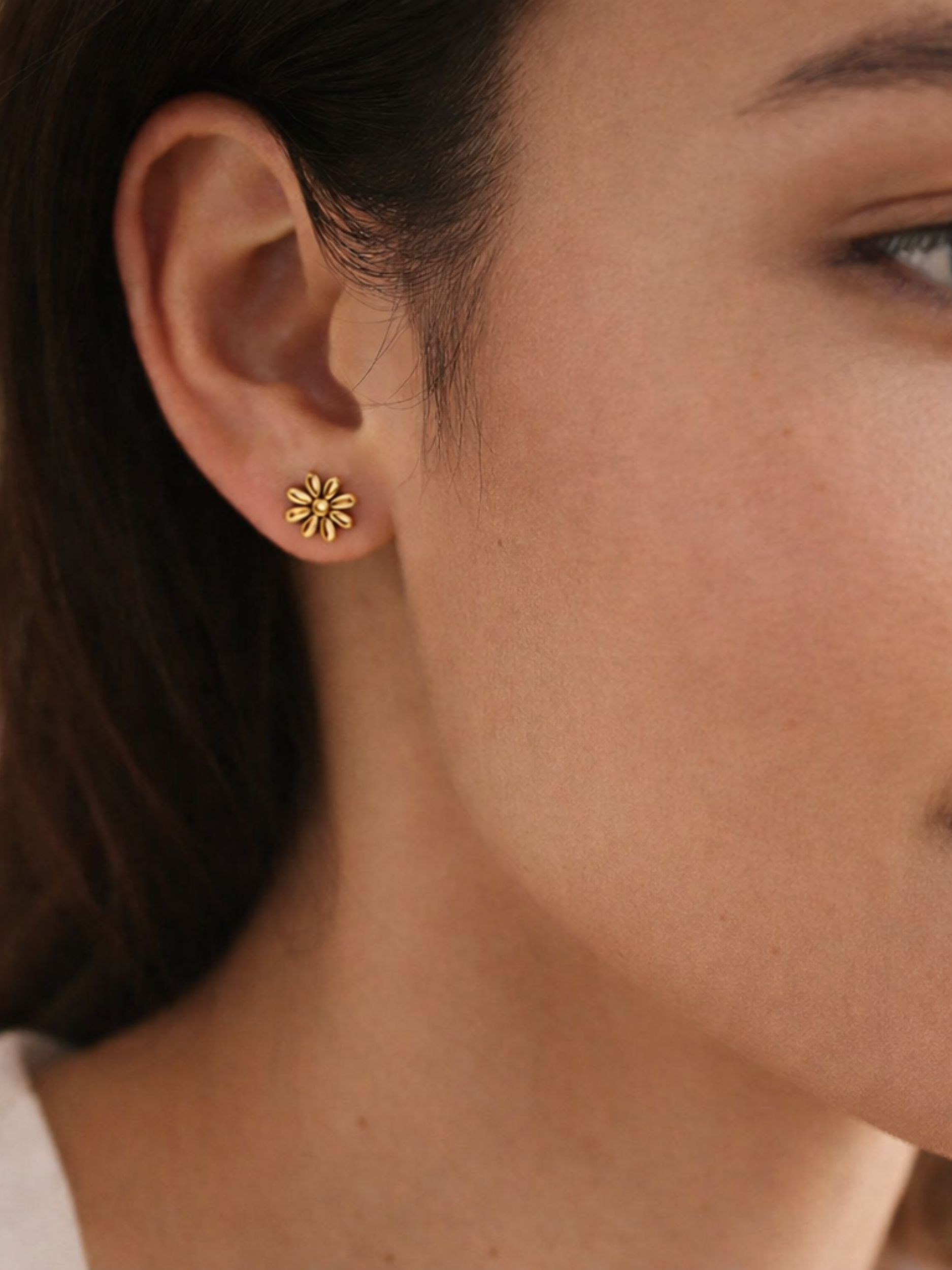 Close-up of a person wearing gold floral earrings.