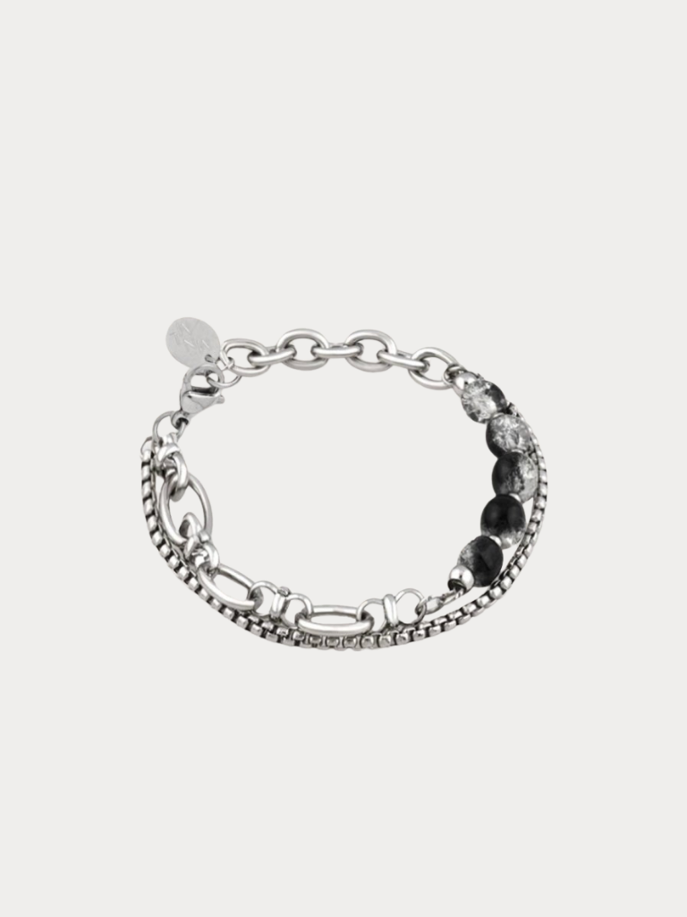 A silver-toned multi-strand chain bracelet featuring textured beaded links, polished oval links, and a row of dark round stones, displayed on a light gray background.