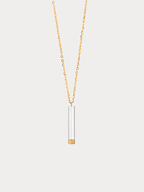 A delicate gold chain necklace featuring a minimalist cylindrical pendant with a white center and a gold-toned base, displayed against a light gray background.