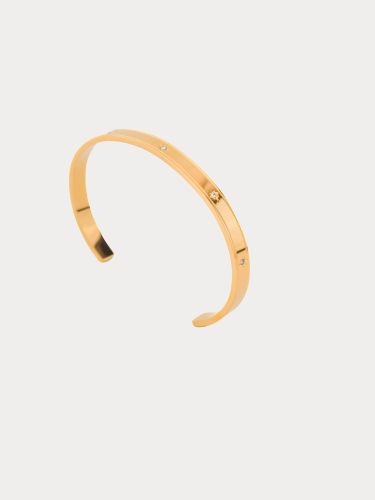 Star Spangled Bangle gold tone stainless steel, flat open cuff with scattered CZ stones, product flatlay