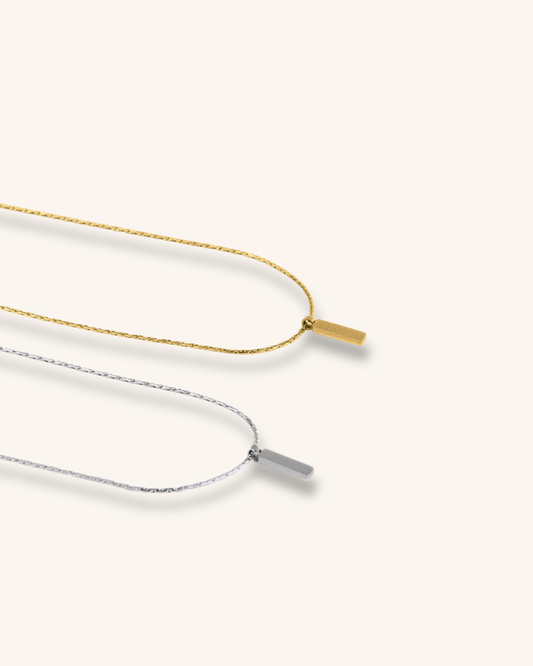 Flat lay of Axis Pendant Wheat Chain Necklace in silver and gold