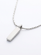 Macro detail of Axis rectangular pendant in silver titanium on wheat chain
