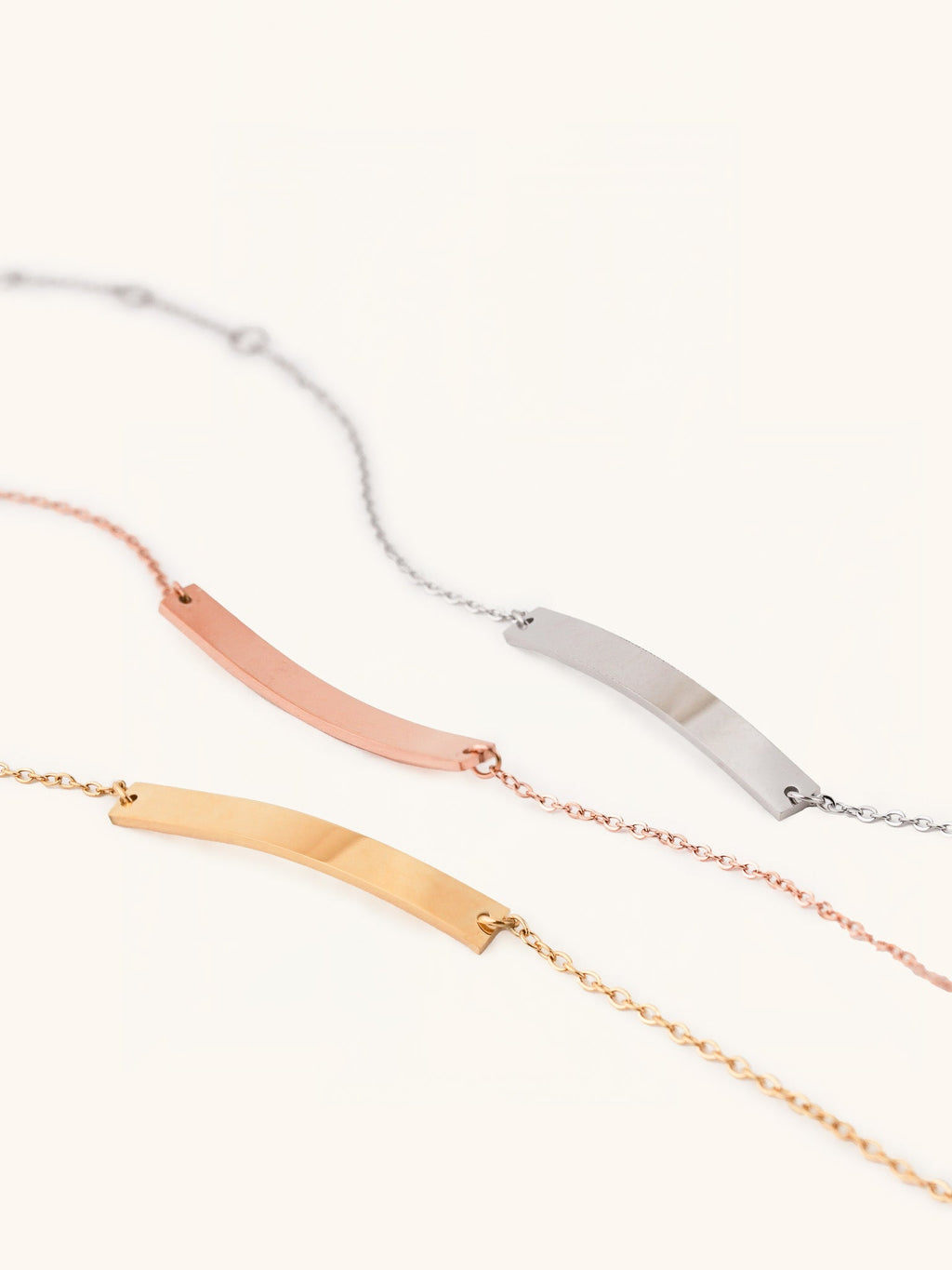 Flat lay of engravable plate bracelet in silver, gold, and rose gold