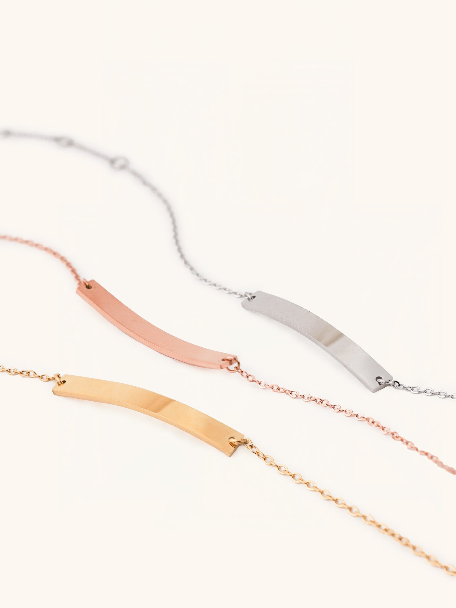 Flat lay of engravable plate bracelet in silver, gold, and rose gold