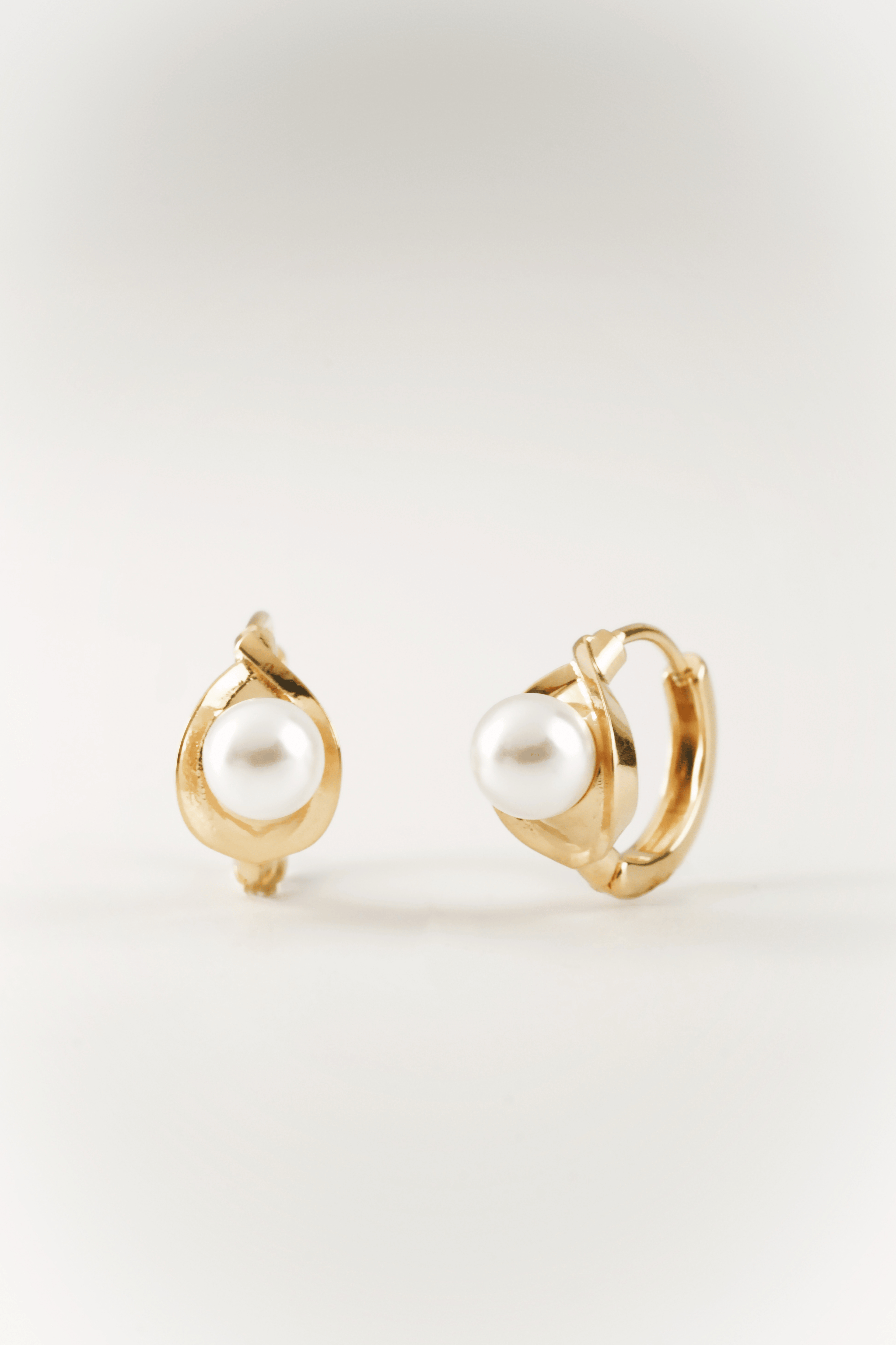 Carina Pearl Huggie Earrings in gold tone PVD stainless steel, sculptural pearl huggie product flatlay