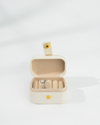 Beige jewelry box with a d-color moissanite ring inside 