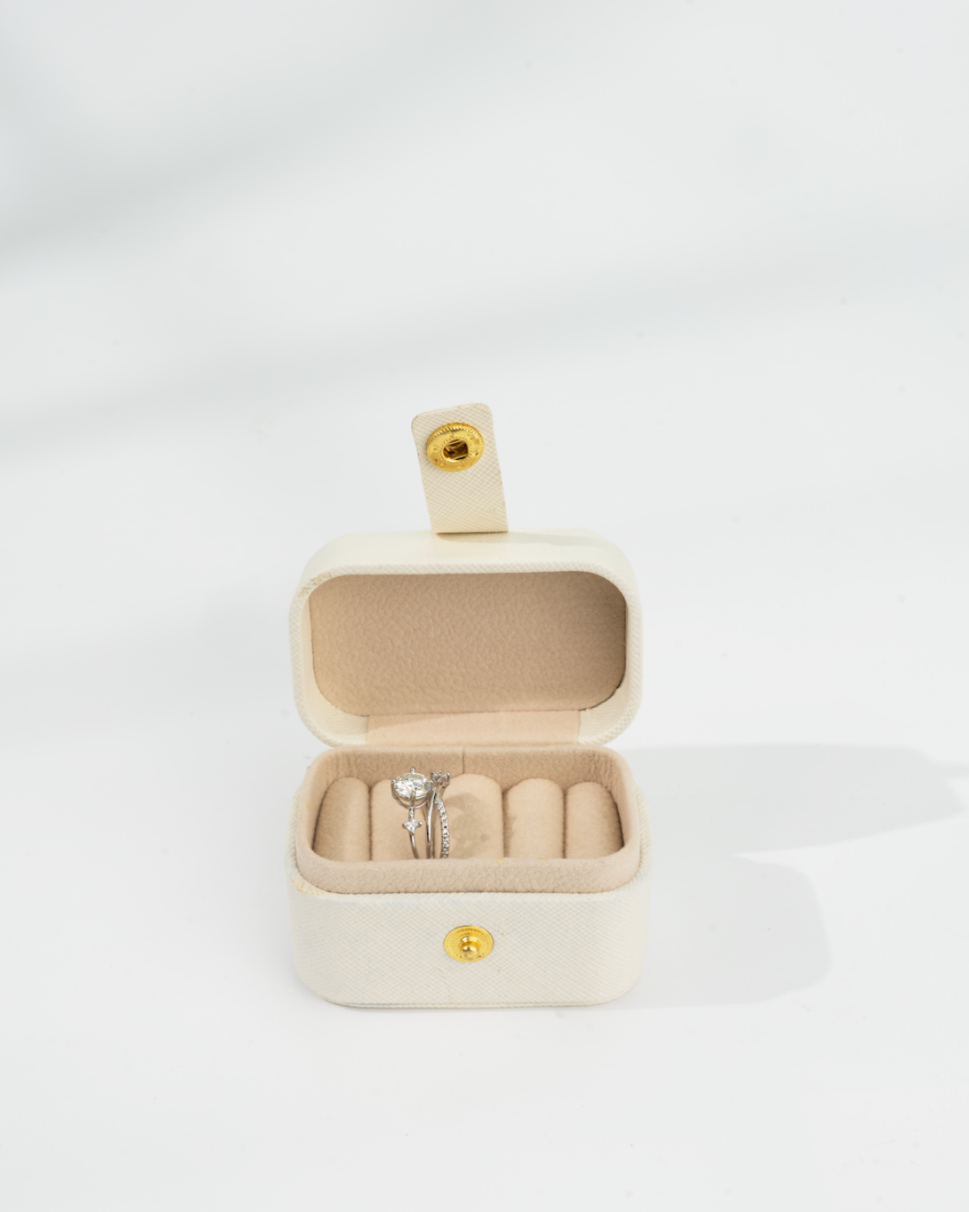 Beige jewelry box with a d-color moissanite ring inside 