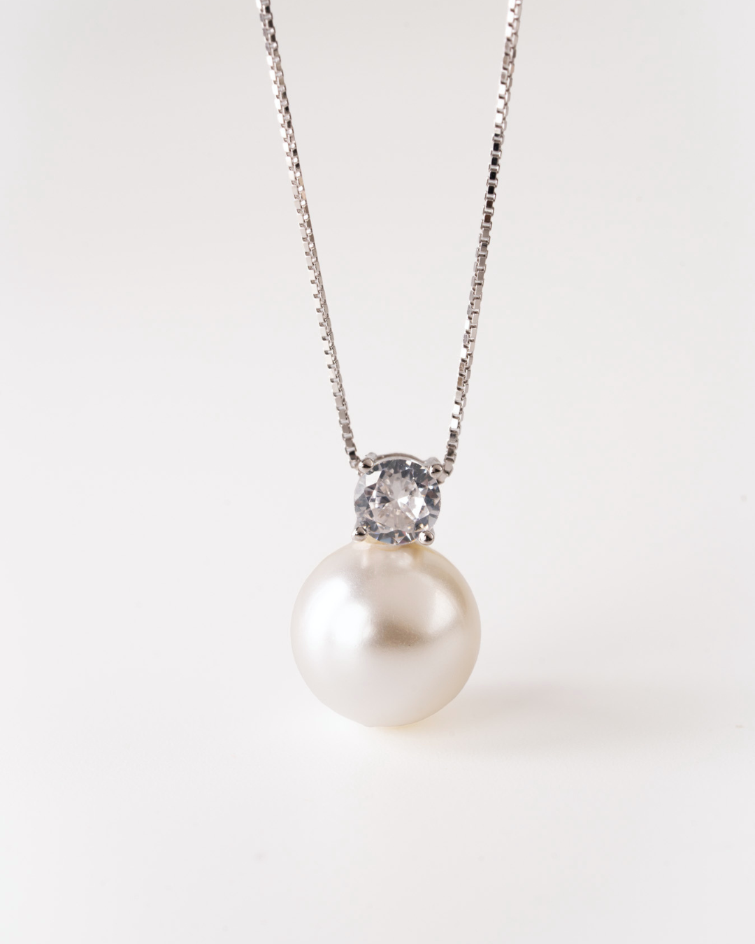 Pearl necklace with a silver chain and gemstone on a white background