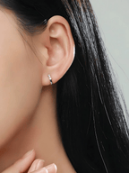 Close-up of three prong-set cubic zirconia stones on Eva Diamond Huggie sterling silver earrings