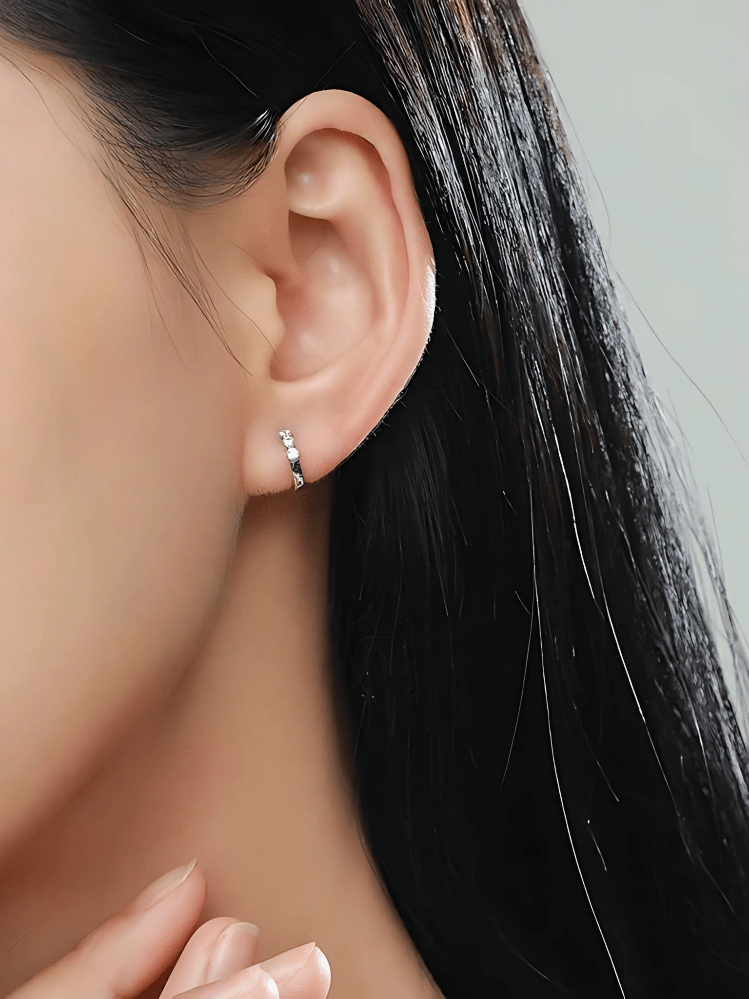 Close-up of three prong-set cubic zirconia stones on Eva Diamond Huggie sterling silver earrings