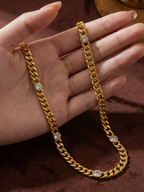 Gold chain with embedded stones held by a hand on a brown background