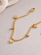 Detail of alternating heart and CZ charms on Jaye Heart Charm Bracelet bead chain, gold tone