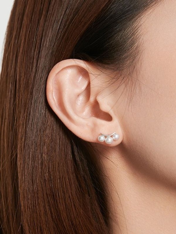 Clara Pearldrift Earrings worn on the ear, triple pearl design