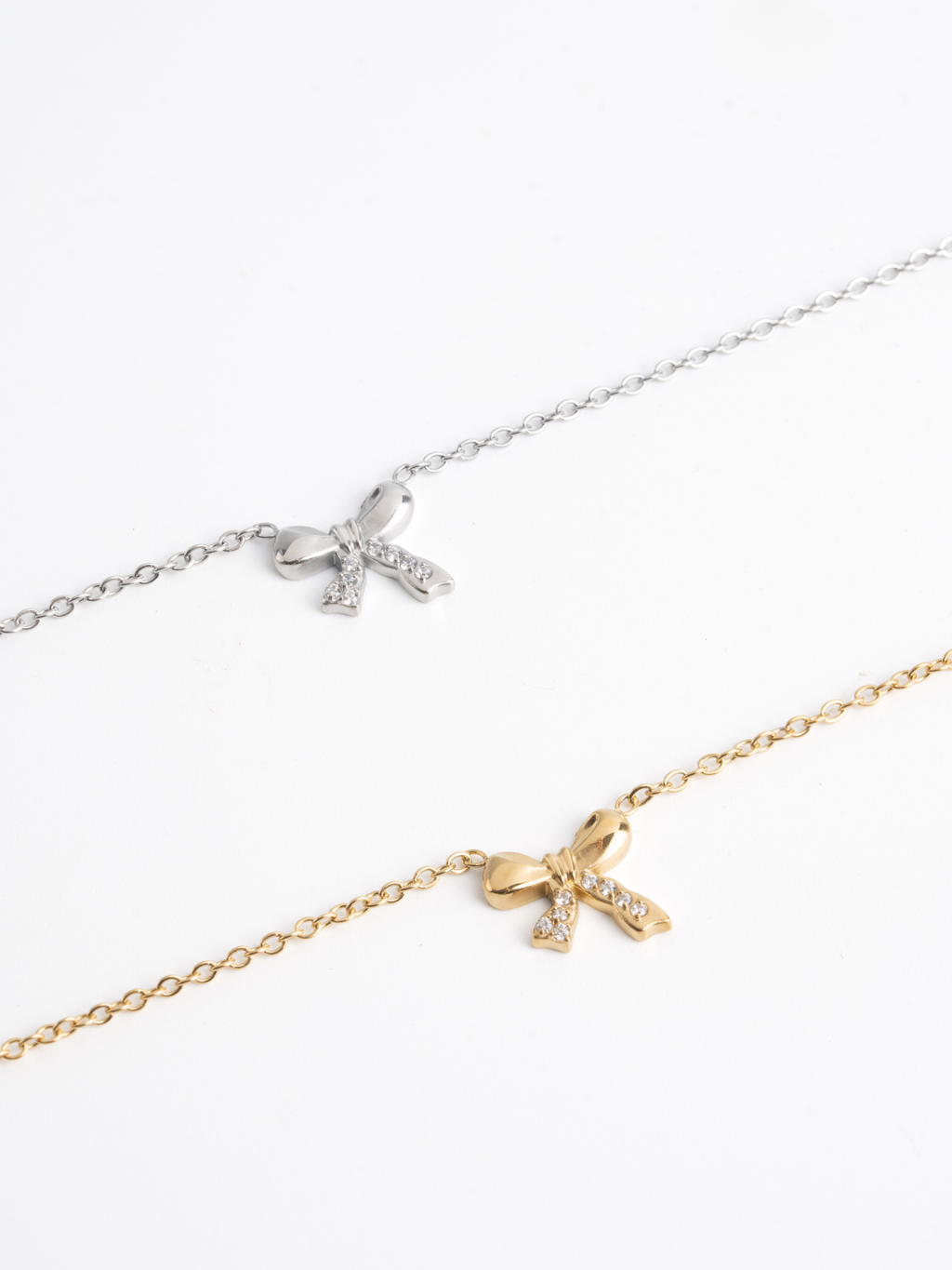 MNML Delicacy Bow Pendant Necklace in silver and gold flat lay — titanium bow jewelry Malaysia