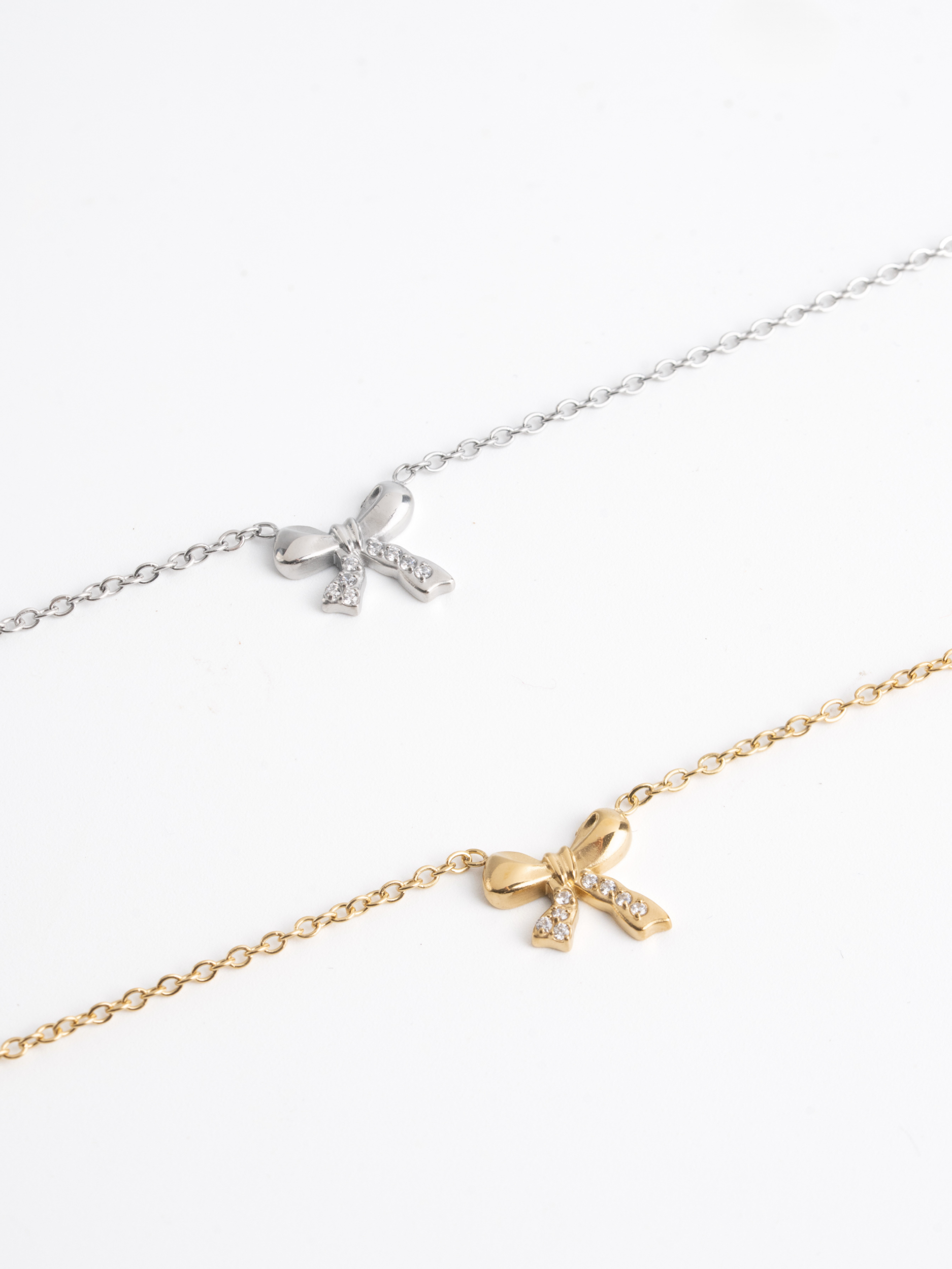 MNML Delicacy Bow Pendant Necklace in silver and gold flat lay — titanium bow jewelry Malaysia