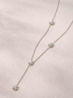 MNML Elia Daisy Lariat Necklace in silver and gold flat lay — stainless steel daisy jewelry