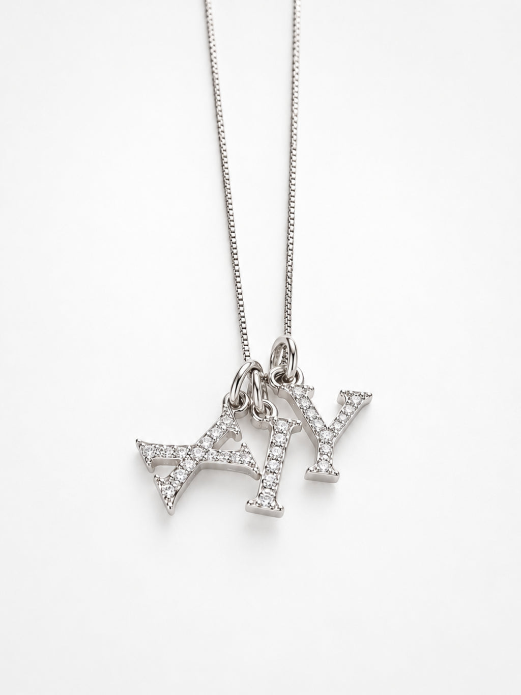 Several initial pendants layered together on one chain