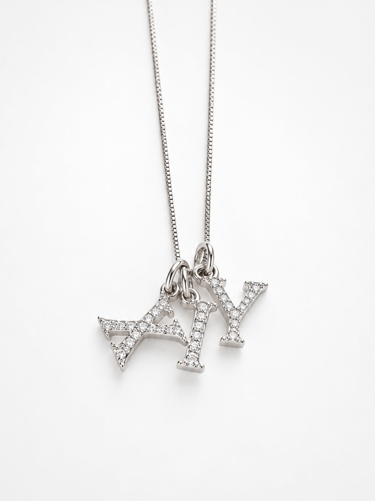 Several initial pendants layered together on one chain