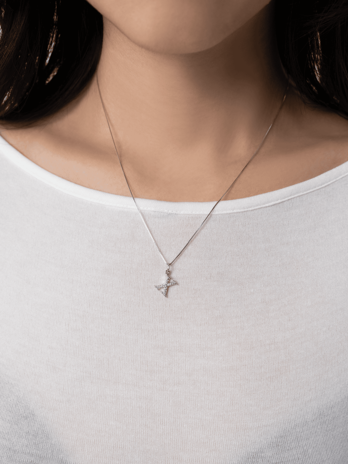 Initial alphabet pendant worn at the neckline on a chain