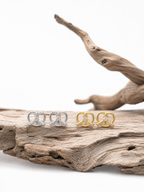 MNML Little Pretzel Stud Earrings in silver and gold flat lay — titanium CZ pretzel earrings