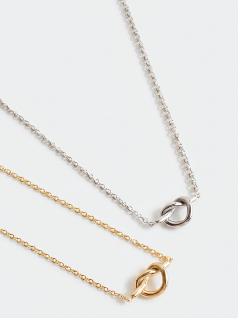 MNML Love Me Knot Necklace in silver and gold flat lay — stainless steel knot jewelry Malaysia