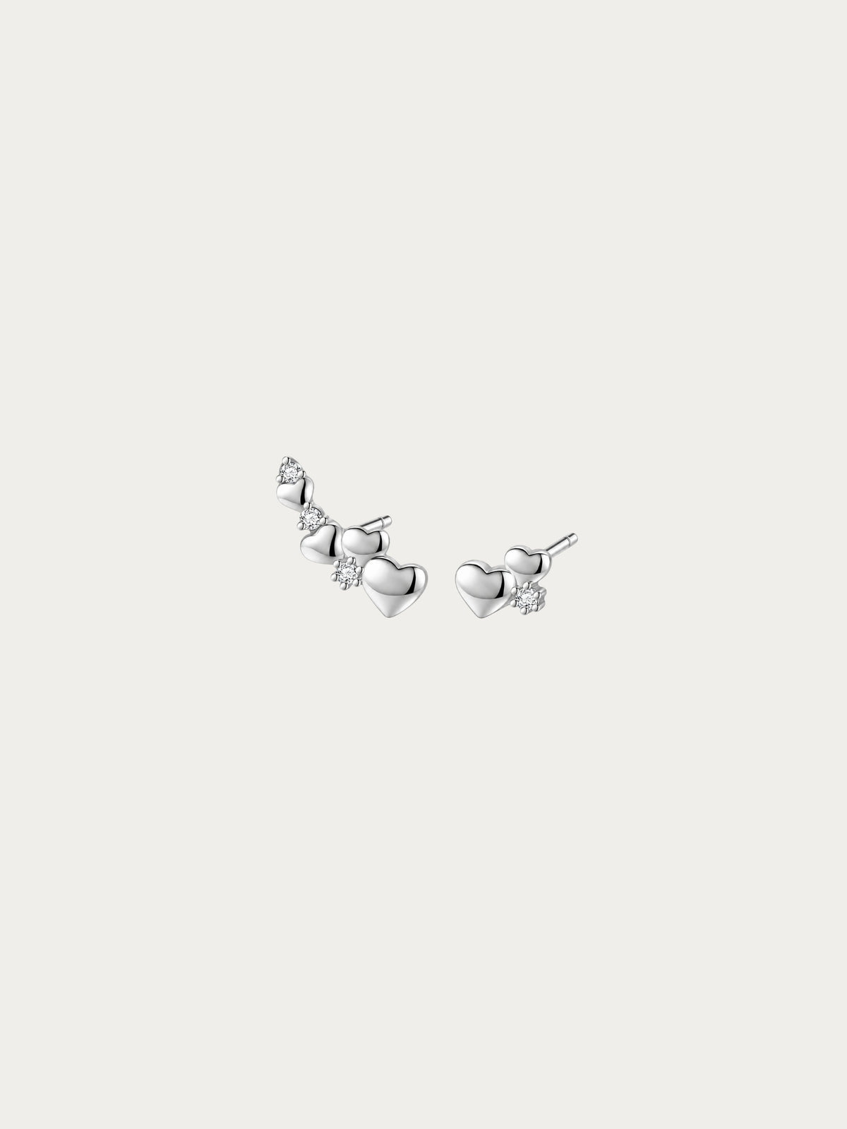 Routine Love asymmetrical heart stud pair in rhodium-plated 925 silver, with a four-heart trail and a two-heart cluster side by side