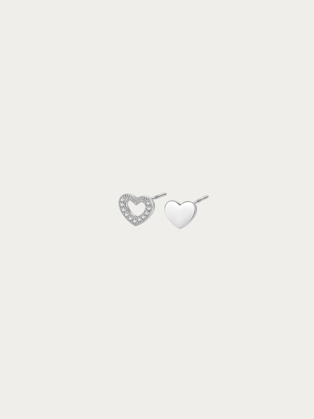 Teeny Tiny asymmetrical heart stud pair in rhodium-plated 925 silver, with an open pavé heart and a solid heart side by side