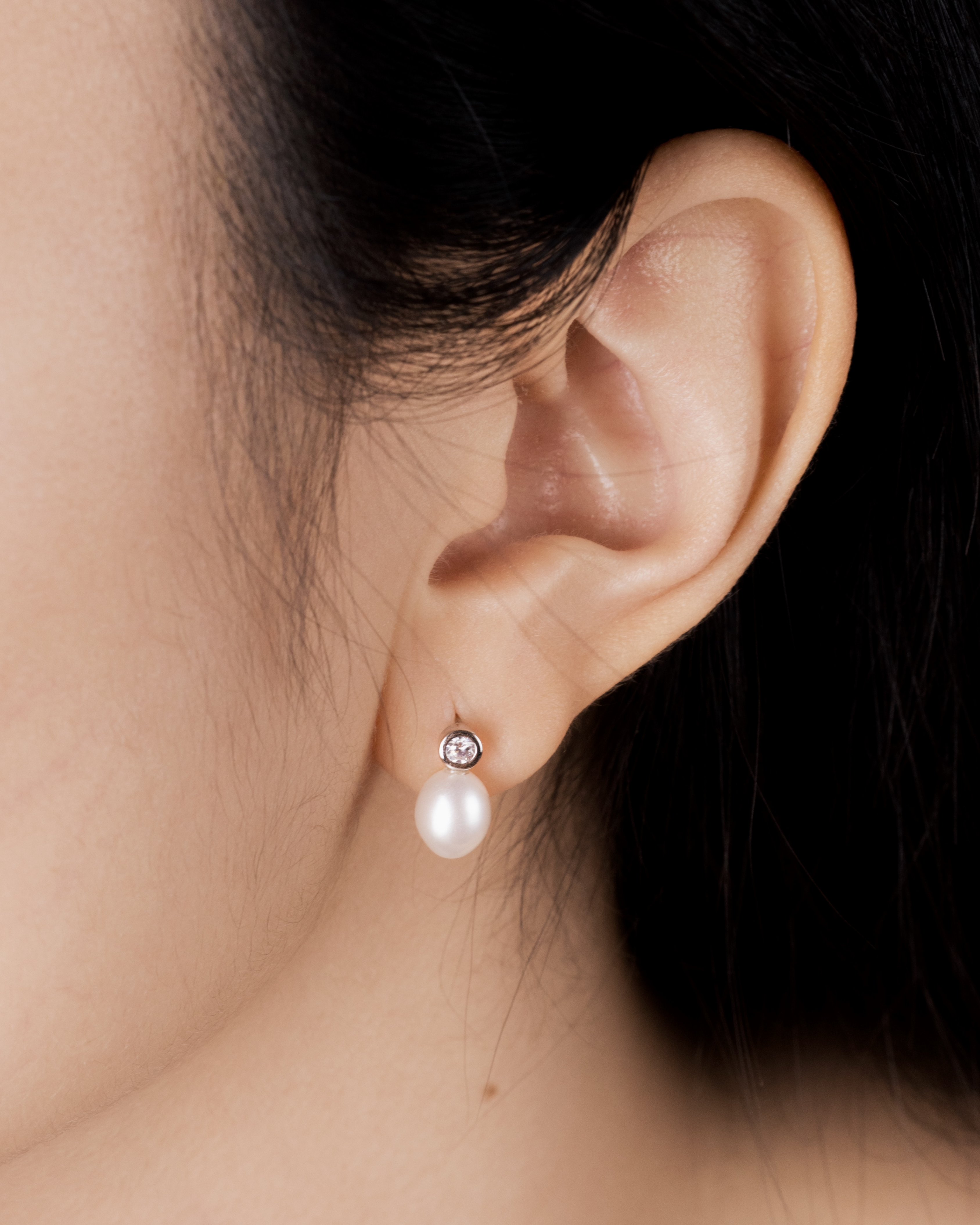 Side view of Tsuki earring showing bezel CZ and oval pearl placement