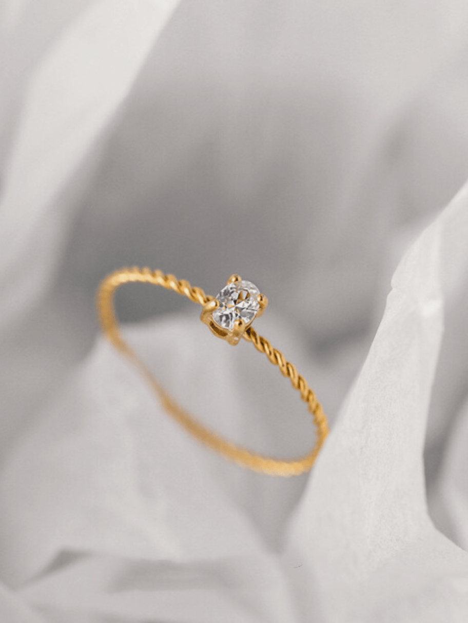 Close-up of oval CZ solitaire stone on Twist Oval Solitaire Ring, gold tone titanium prong setting
