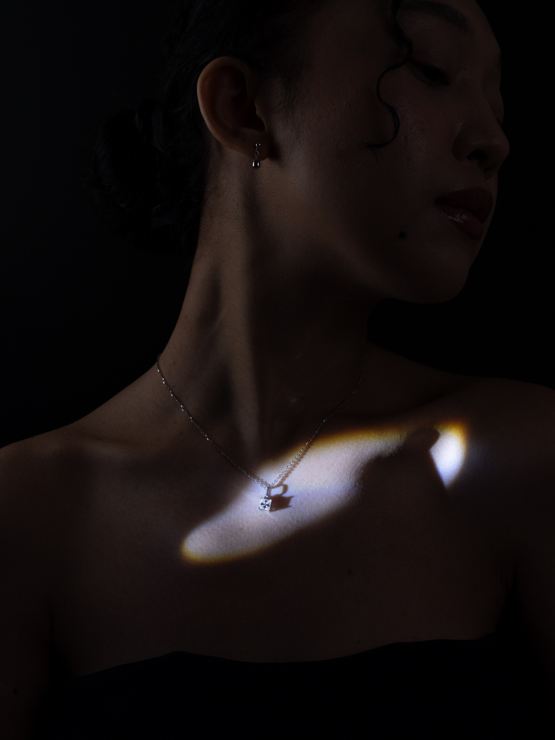 Winifred princess-cut moissanite necklace worn on neckline in dramatic lighting