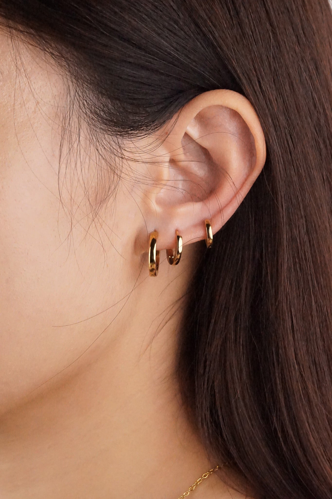 Model wearing MNML Oliva titanium huggie hoop earrings — snug fit, clean minimalist silhouette