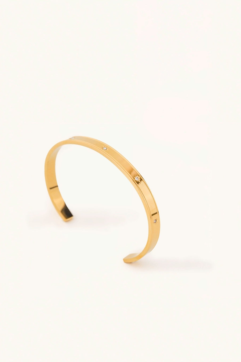Star Spangled Bangle gold tone stainless steel, flat open cuff with scattered CZ stones, product flatlay