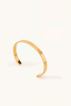 Star Spangled Bangle gold tone stainless steel, flat open cuff with scattered CZ stones, product flatlay